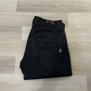 Svarta straight jeans från Dondup - Svarta jeans från Dondup med klassisk femficksdesign och metall-D på bakfickan. Modellen har rak passform och normal midja, tillverkade i slitstarkt bomullsmaterial. Perfekt för dig som gillar stilrena och tidlösa jeans med snygga detaljer.
