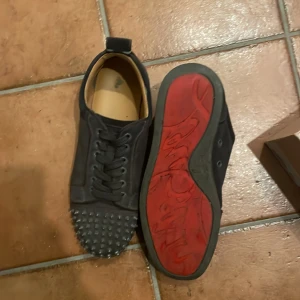 Christian Louboutin - Säljer ett par svarta Christian Louboutin skor med nitar och ikonisk röd sula. Levereras med originalkartong, dustbag och tillbehör samt kvitto.
