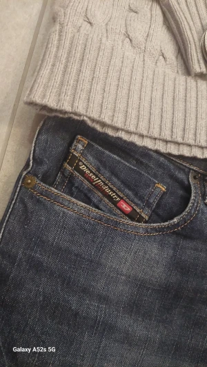 Mörkblå jeans från Diesel - Säljer ett par snygga mörkblå jeans från Diesel med klassisk femficksdesign och diskreta slitningar. Jeansen har raka ben och tydliga kontrastsömmar. Märkespatch bak i midjan och Diesel Industry-detalj vid fickan. Perfekta för dig som gillar en stilren och avslappnad look.