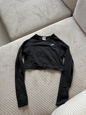 Svart croppad långärmad topp Gymshark - Säljer en svart croppad långärmad topp från Gymshark. Toppen har en tight passform,  storlek m men skulle säga att den passar S bättre 