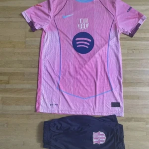 Barça Raphinha 11 rosa matchtröja - Säljer en Barcelona fotbollströja med Raphinha 11 på ryggen. Tröjan är rosa med blå detaljer, har korta ärmar och är tillverkad i lätt, ventilerande material. Fram finns Spotify-logga och klubbmärke, bak UNHCR-tryck. Shorts i mörkblått med klubbmärke ingår.