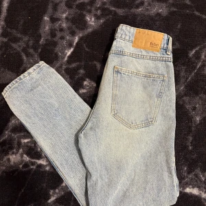 Ljusblå jeansbyxor från FSBN - Säljer ett par klassiska ljusblå jeans från FSBN. Byxorna har fem fickor, raka ben och en snygg läderpatch med logga bak i midjan. Perfekta för en avslappnad och tidlös stil.