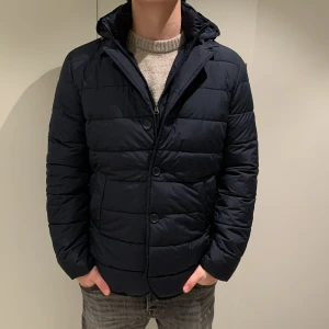 Limiterad jacka från John Henric  - Snygg mörkblå pufferjacka med avtagbar huva. Köpte jackan från John Henric men säljs pga att den va en storlek för stor! ( Jag är 178cm och väger runt 75kg) Tveka inte på att höra av dig om du har fler frågor! (Aldrig använd)