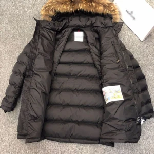 Svart Moncler cluny med pälskrage - Svart dunjacka från Moncler med fluffig pälskrage i bruna toner. Jackan har quiltad design, dragkedja och knappar framtill samt flera fickor. Perfekt för kalla dagar och har en klassisk Moncler-logga på ärmen. Storlek 3 vilket motsvarar L