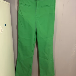 Gröna kostymbyxor från Zara, stl S - Snygga gröna kostymbyxor från Zara i storlek S. Byxorna har raka ben, diskreta fickor fram och är tillverkade i ett mjukt material med stretch. Perfekta för dig som vill sticka ut med färg och stil. Sitter tajt och formar kroppens former men på ett bekvämt sätt då de har mycket stretch. För bild på, skiivka ett meddelande