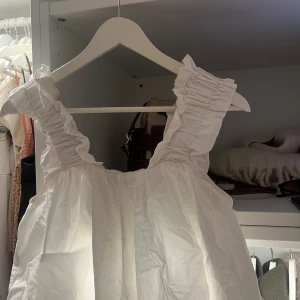 Vit volangärmad linnetopp - Supersöt vit linnetopp med breda axelband och volangdetaljer. Toppen har en luftig och flowy passform.🤍