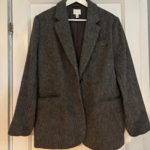 Grå kappa H&M - Elegant och tidlös grå kappa i klassisk design. Modellen har två praktiska framfickor och en rak, smickrande passform som passar både till vardag och fest. Perfekt för höst och vår! Materialet är mjukt och bekvämt