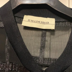 Malene Birger - Säljer en svart blus från By Malene Birger glittriga ränder i ett rutigt mönster. Blusen har rund halsringning och korta ärmar. Den är i jätte bra skick och lite oversized PRIS KAN DISKUTERAS!