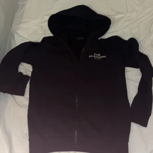 Svart hoodie Peak Performance  - Svart hoodie från Peak Performance i storlek 170. Tröjan har huva, hel dragkedja framtill och lång ärm. Diskret logga broderad på bröstet. Perfekt för chill eller när du vill ha en enkel och snygg look.