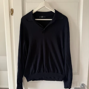 Svart långärmad pikétröja från MNG - Svart långärmad pikétröja från MNG med klassisk krage och v-ringning. Tröjan är i mjukt material och har ribbade muddar vid ärmslut och nederkant. Perfekt för en clean och stilren look.