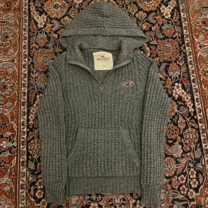 Vintage stickad hollister hoodie - Riktigt fet vintage stickad Hollister hoodie! Dessa har blivit extremt eftertraktade senaste så därav priset! Bra skick inga konstigheter!  Mått: Bredd: 49,5cm Längd: 62cm