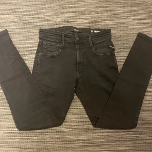 Svarta Replay Anbass jeans - Säljer ett par snygga replay jeans! Jeansen är i mycket bra skick förutom en liten missfärgning på bakfickan samt en liten fläck vid låret som förmodligen går bort i tvätten, man ser knappt fläcken när jeansen sitter på. Annars mycket fina! Om ni har några frågor så är de bara att höra av er😁