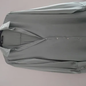 Mint grön satinblus från Zara - Supersnygg Mint grön blus från Zara i glansigt satinmaterial. Klassisk krage, långärmad och med knappar framtill. Perfekt för dig som gillar stilrena och moderna plagg med en lyxig känsla. Passar dig som vill ha en enkel men elegant look.