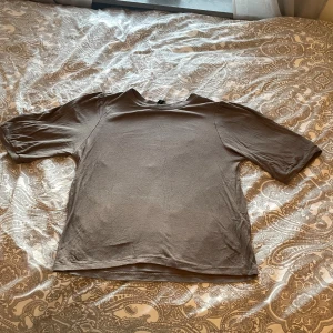 Brun kortärmad blus med puffärm - Säljer en enkel brun blus med rund hals och korta puffärmar. Toppen har en rak passform och är gjord i mjukt bomullsmaterial som känns skönt mot huden. Perfekt att matcha med jeans eller kjol för en chill look.