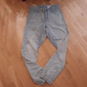 Ljusblå jeansbyxor från &NOW - Ljusblå jeansbyxor från &NOW Limited Edition med elastiska benslut, stora bakfickor och snygga detaljer vid fickorna. Byxorna har normal passform och är tillverkade i mjukt jeanstyg. Perfekta för en avslappnad och trendig look.