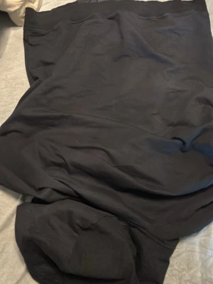 Svart Nike Air vindjacka med huva - Svart Nike Air vindjacka med huva och dragkedja framtill. Jackan har två sidofickor med dragkedja och Nike Air-logga på bröstet. Materialet är lätt och syntetiskt, perfekt för att hålla vinden ute. Enkel och stilren design som funkar till streetwear.