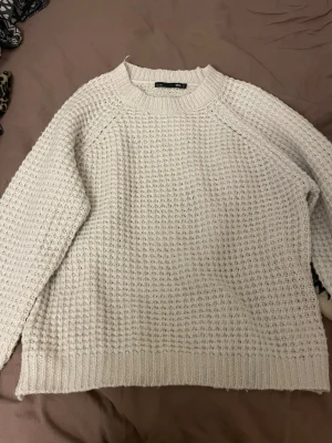 Vit stickad tröja från 157 - Säljer en vit stickad tröja från 157 i storlek S. Tröjan har ett grovt, strukturerat mönster och ribbade muddar vid hals, ärmslut och nederkant. Perfekt för kyliga dagar och enkel att matcha med jeans eller kjol.