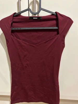Vinröd topp från Bik Bok - Säljer en vinröd topp från Bik Bok i mjuk bomull. Toppen har en v-ringad hals och är kortärmad med en slim passform. 