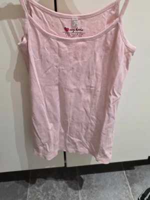 Ljusrosa linnetopp från Bonprix - Säljer en ljusrosa linnetopp från Bonprix Collection, modell My Basic. Toppen har smala axelband och ärmlös design, tillverkad i mjuk bomull. Perfekt för varma dagar och enkel att matcha med jeans eller shorts.