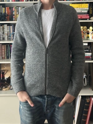 Grå stickad kofta från Devred - Säljer en grå stickad kofta från Devred med dragkedja framtill och ståkrage. Koftan har långärmad design och är tillverkad i ett mjukt stickat material som känns skönt mot kroppen. Nypris ca 1500