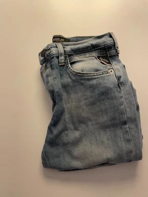 Ljusblå Replay jeans, rak modell - Säljer ett par ljusblå jeans från Replay med klassisk femficksdesign och raka ben. Jeansen har snygga slitningar och Replay-logga på fickan. Tillverkade i mjukt jeanstyg som sitter skönt hela dagen.