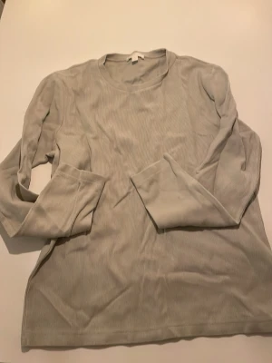 Ljusbeige ribbad långärmad tröja COS - En stilren ljusbeige långärmad tröja från cos. Tröjan har en ribbad struktur och rund halsringning, vilket ger en enkel men trendig look. Perfekt att matcha med jeans eller kjol för en avslappnad stil.