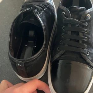 Lanvins - Snygga svarta Lanvins med vit sula och lackad tådel. Ovandelen är i mocka och skorna har klassisk snörning. Perfekta för dig som gillar en stilren look med en twist. Passar till det mesta och är riktigt bekväma. Skicket är bra. De har används men har fof mycket kvar att ge. mockan är  trött men de går nog att fixa med en mockaborste om man orkar göra det. jag har inte haft orken. Sulan är målad vit med skofärg så de går bort men de är bara att måla över igen