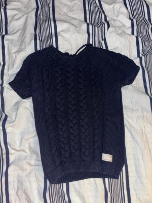 Mörkblå stickad tröja från Odd Molly - Säljer en mörkblå stickad tröja från Odd Molly. Den har knyten bak på ryggen och utbroderade siffror