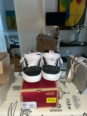 Svarta och vita Vans Knu skool  - Säljer ett par klassiska Vans sneakers i svart och vitt med vit sula och snörning. Skorna har en låg profil och är tillverkade i canvas och mocka, med den ikoniska Vans-loggan på plösen. Perfekta för dig som gillar streetstyle och skate. Äkta och knappt använda. Pris kan diskuteras. 