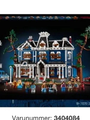 Lego - Bilden visar ett stort blått och vitt leksakshus med flera minifigurer framför.