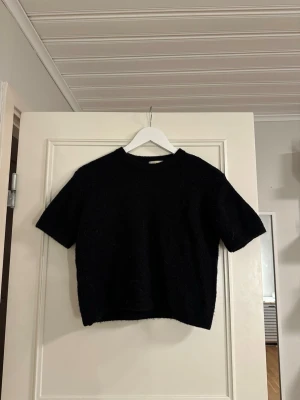 Svart stickad topp Gina Tricot - En svart, kortärmad stickad topp från Gina Tricot. Mjuk och bekväm, perfekt som basplagg och enkel att styla till både vardag och till mer uppklädda outfits. Säljer den eftersom den tyvärr inte kommer till användning längre. I gott skick, inga defekter.