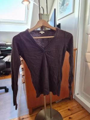 Mörkbrun stickad v-ringad tröja Bik Bok - Säljer en mörkbrun stickad tröja från Bik Bok i storlek XS. Tröjan har v-ringad hals och långa ärmar, med en snygg rynkning framtill vid halsen. Perfekt för dig som gillar enkel och stilren design med mjukt material.