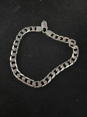 Snygg silverfärgad kedjehalsband - Kedjehalsband i silverfärg med klassisk, platt länkkedja. Passar perfekt till en clean och stilren look. Halsbandet har ett smidigt lås och är lätt att matcha med andra accessoarer. Halsband: 52cm. Kvitto finns på den första ringen.