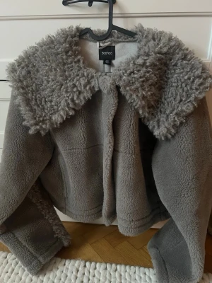 Grå teddyjacka - Säljer en fluffig grå teddyjacka från Boohoo med stor krage och markerade sömmar. Passar även om man är en storlek M 