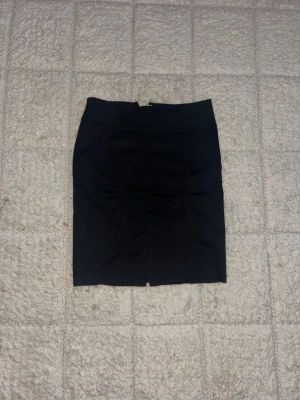 Svart kjol H&M - Säljer en svart kjol från H&M i storlek 34. Kjolen har en klassisk, rak form med diskret slits bak och dragkedja i ryggen. Materialet är mjukt och bekvämt, perfekt för dig som gillar stilrena och enkla plagg. Passar dig som vill ha en snygg och tidlös look.