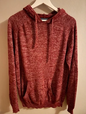 Stickad mörkröd hoodie - Säljer en mörkröd stickad hoodie. Den är i st M men skulle säga att den passar bättre som L. Den passar dig som gillar grisch stilen eller stickade tröjor. Den passar bra på sommaren men även inomhus på kallare tider. Den har huva med snören som kommer fram på framsidan och en känguruficka. Priset är inte hugget i sten. Skriv vid minsta funderingar!