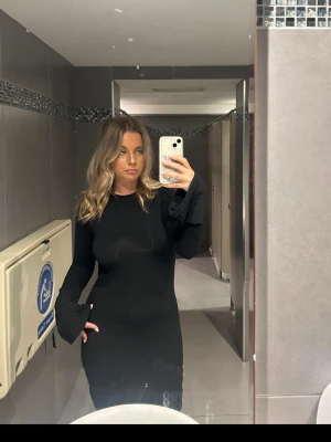 Svart långärmad klänning Boohoo - En svart, figurnära kortklänning från Boohoo med långa ärmar och rund halsringning. Klänningen har en enkel och stilren design i stretchigt material som sitter snyggt på kroppen. Perfekt för dig som gillar en clean look och vill ha något som funkar till många tillfällen.