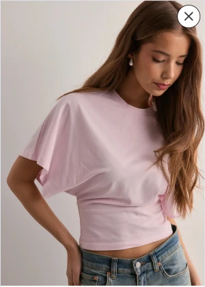 Ljusrosa croppad t-shirt med vida ärmar - Säljer en ljusrosa croppad t-shirt från Nelly. (Dem tre första bilderna är ej mina). T-shirten är lös upptill och tajt ner till.🩷 Den har aldrig använts och har även lappen kvar. Den har ett stretchigt och mjukt kvalite🫶💓  