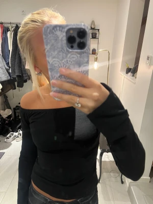 Svart offshoulder långärmad topp - Säljer en svart långärmad topp med offshoulder-design. Toppen har en tight passform och är tillverkad i ett mjukt och stretchigt material som sitter snyggt mot kroppen. Perfekt för dig som gillar stilrena och enkla plagg med en modern touch.