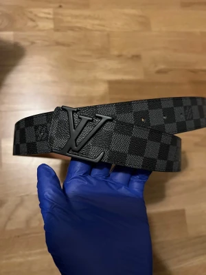 Louis vuitton bälte - Säljer mitt snygga Louis Vuitton-bälte i svart skinn med det klassiska LV-mönstret i svart. Helt ny och oanvänd skärp. Perfekt om du vill ge outfiten lite extra lyxig känsla. Vid minsta fundering – tveka inte på att höra av er!