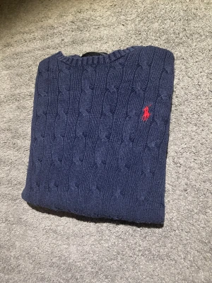 Sweater Polo Ralph Lauren Cable Knit 🧶 - Sweater Polo Ralph Lauren Cable Knit 🧶  Navy blue cable knit sweater by Polo Ralph Lauren with iconic red logo. Appears in excellent condition with no visible flaws.  ⭐️ Condition: 7,5/10 🎲 Size: M 🎨 Color: Navy Blue 📦 Fast and careful shipping