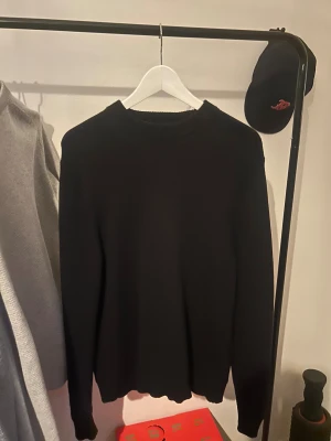 Svart stickad tröja från Selected Homme - En stilren svart stickad tröja från Selected Homme. Tröjan har rund halsringning och långa ärmar med ribbade muddar. Oanvänd!