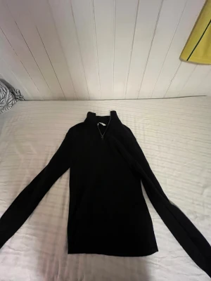 Svart merinoulltröja med half zip - Svart långärmad tröja från Cubus i 100% merinoull. Tröjan har en stilren design med hög krage och half zip-dragkedja framtill. Perfekt för dig som gillar mjuka och värmande material och vill ha en enkel, snygg look.