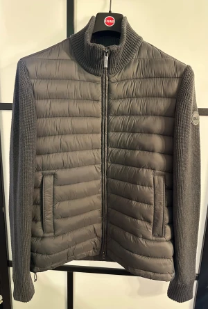 Colmar vinter cardigan - Snygg svart pufferjacka från Colmar med stickade ärmar och krage. Jackan har quiltad framsida, två fickor med dragkedja och en diskret logga på ärmen. Perfekt nu för vintern! Skicket är 9/10, knappt använd. Nypris: 4000kr. Mitt pris: 1250kr. Kvitto finns! Skriv vid intresse 😁