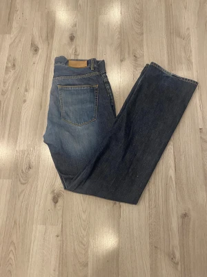 Blå jeans från Emilio, storlek 31 - Snygga blå jeans från Emilio i klassisk modell med raka ben och normal passform. Jeansen har tydliga gula sömmar, fem fickor och är tillverkade i slitstarkt denimtyg. Perfekt för dig som gillar en enkel och tidlös stil.