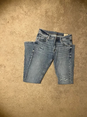 Blå skinny jeans från Jack & Jones - Snygga blå skinny jeans från Jack & Jones med slitna detaljer på benen. Jeansen har normal passform och är tillverkade i bomullsmaterial för en bekväm känsla. Perfekt för dig som gillar en modern stil. Nypris 900kr mitt pris 400kr! Vid frågor bara skriv// Almen 