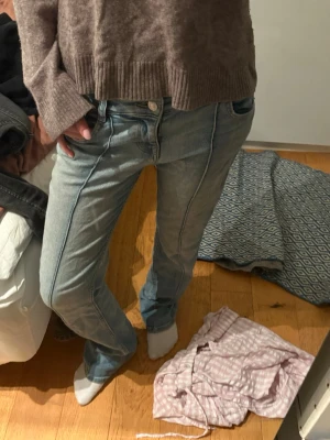 Bershka jeans - Säljer ett par ljusblå jeans med markerade sömmar längs benen och klassisk femficksdesign. Modellen har bootcut-snitt som ger en schysst siluett och är tillverkade i mjukt denim-material. Perfekta för dig som gillar retrovibbar och vill ha något som sticker ut lite.