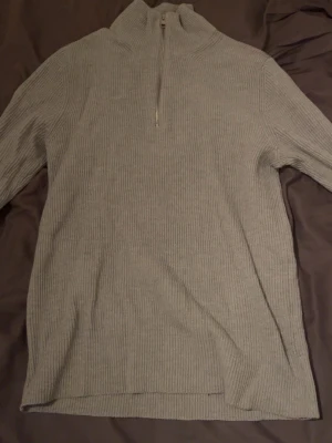 Grå ribbad half zip tröja Jack & Jones storlek M - Säljer en grå ribbad stickad tröja från Jack & Jones Premium i storlek M. Tröjan har en hög krage med half zip-dragkedja och långa ärmar. Perfekt för dig som gillar stilrena och bekväma plagg med lite edge.