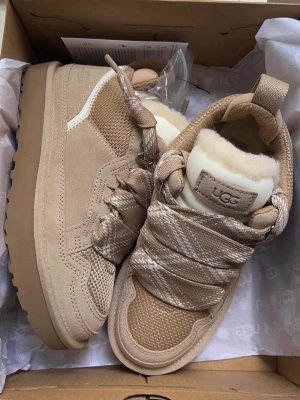 Beige UGG sneakers med fårull - Chunky sneakers från UGG i beige mocka och mesh med breda mönstrade snören och fluffig fårull på insidan. Säljer vidare då de inte passar mig. Passar jättefint för er som bär 38-39 ❤️ postar samma dag. Tillbehör som låda och extra skosnöre följer med. 