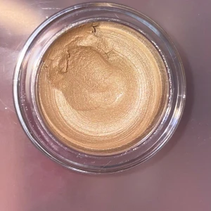 Moira Everlust Shimmer Cream Shadow Champagne - Krämig ögonskugga i burk från koreanska märket Moira i nyansen 02 Champagne Kiss. Färgen är skimrande champagne-guld med metallic finish. Perfekt för att skapa en glowy look. Kommer i en rund glasburk med spegelblankt lock. Endast testad/swatchad med applikator. 